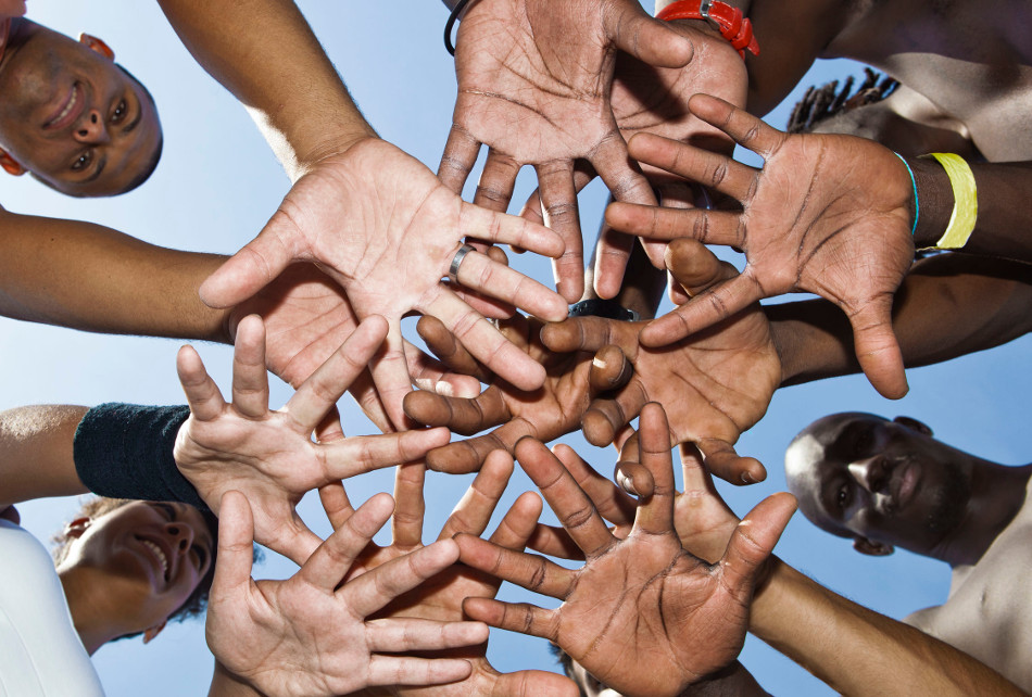 Group of people putting their hands in the middle of a circle