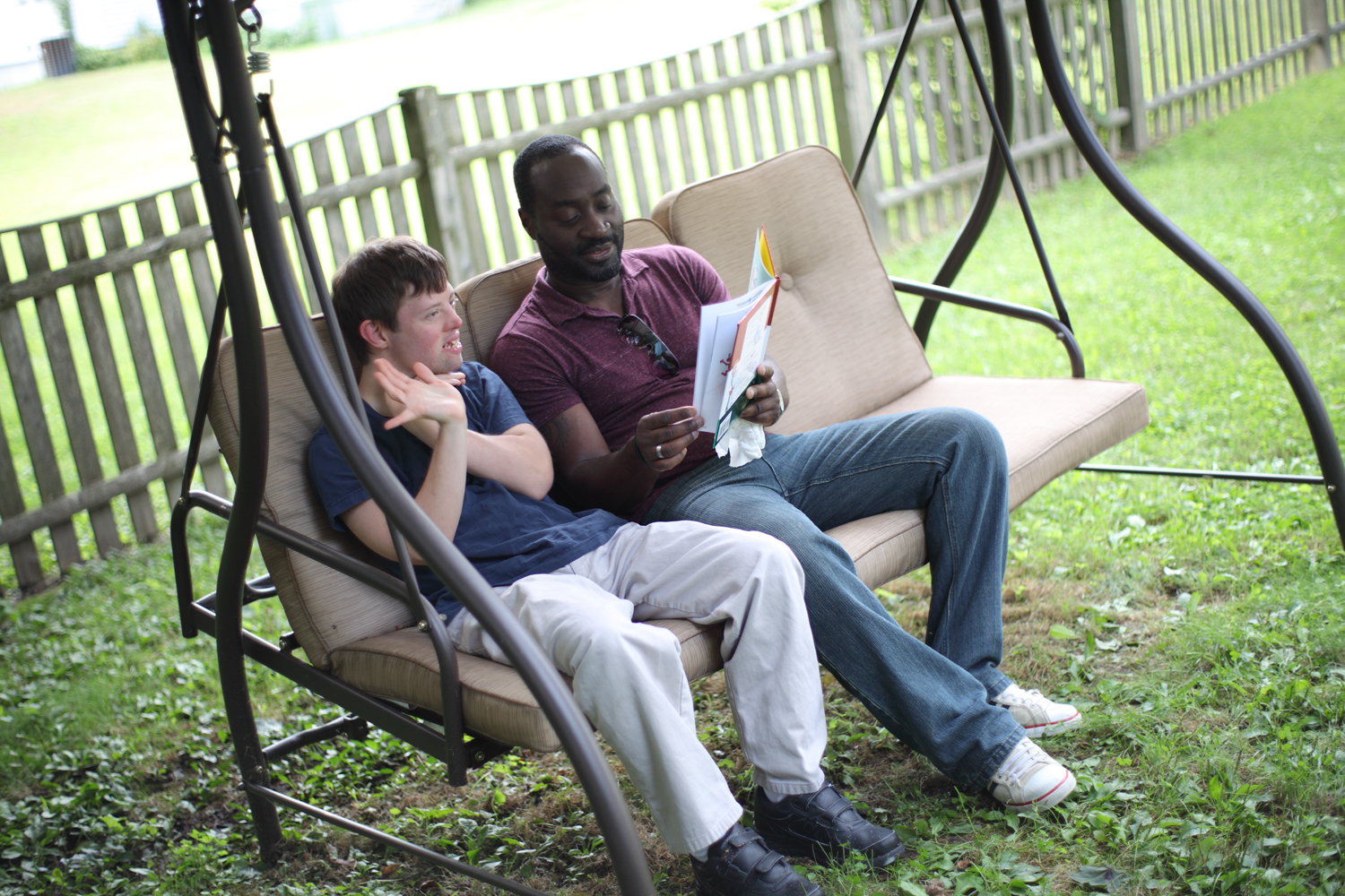 two men on a swing, one with developmental disabilities