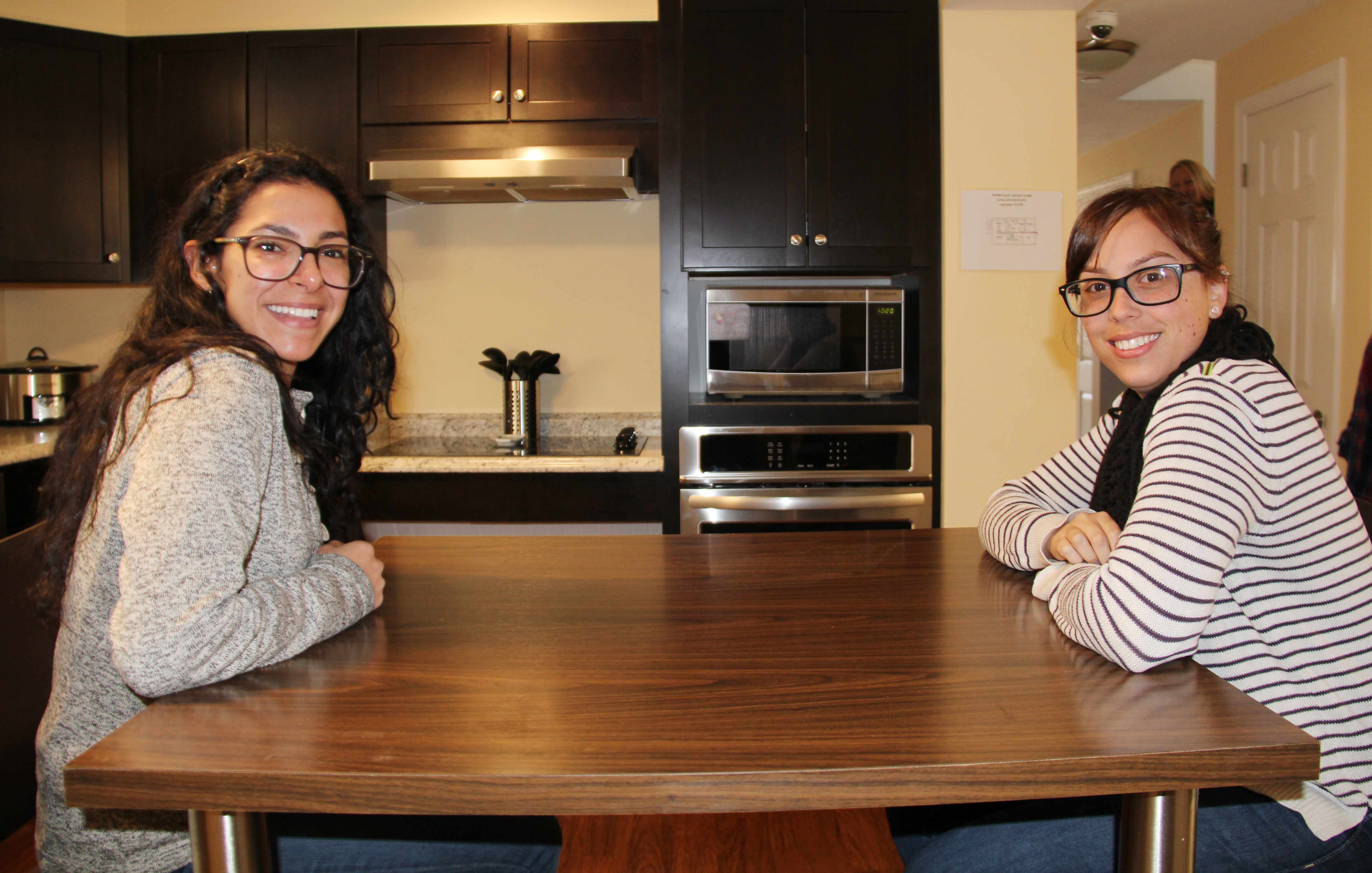 Two girls sitting at table in group home.