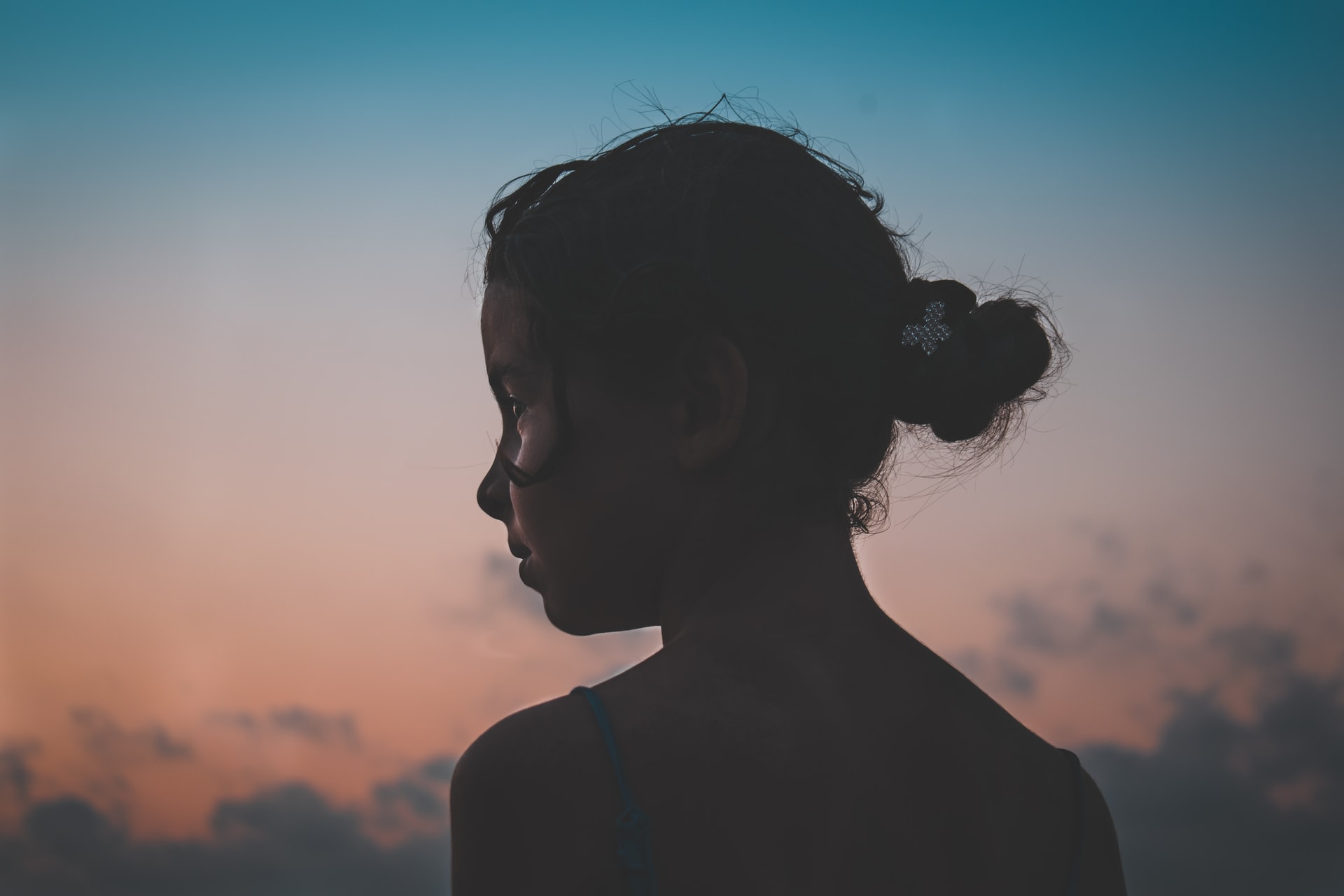 A silhouette of a girl against a sunset sky.