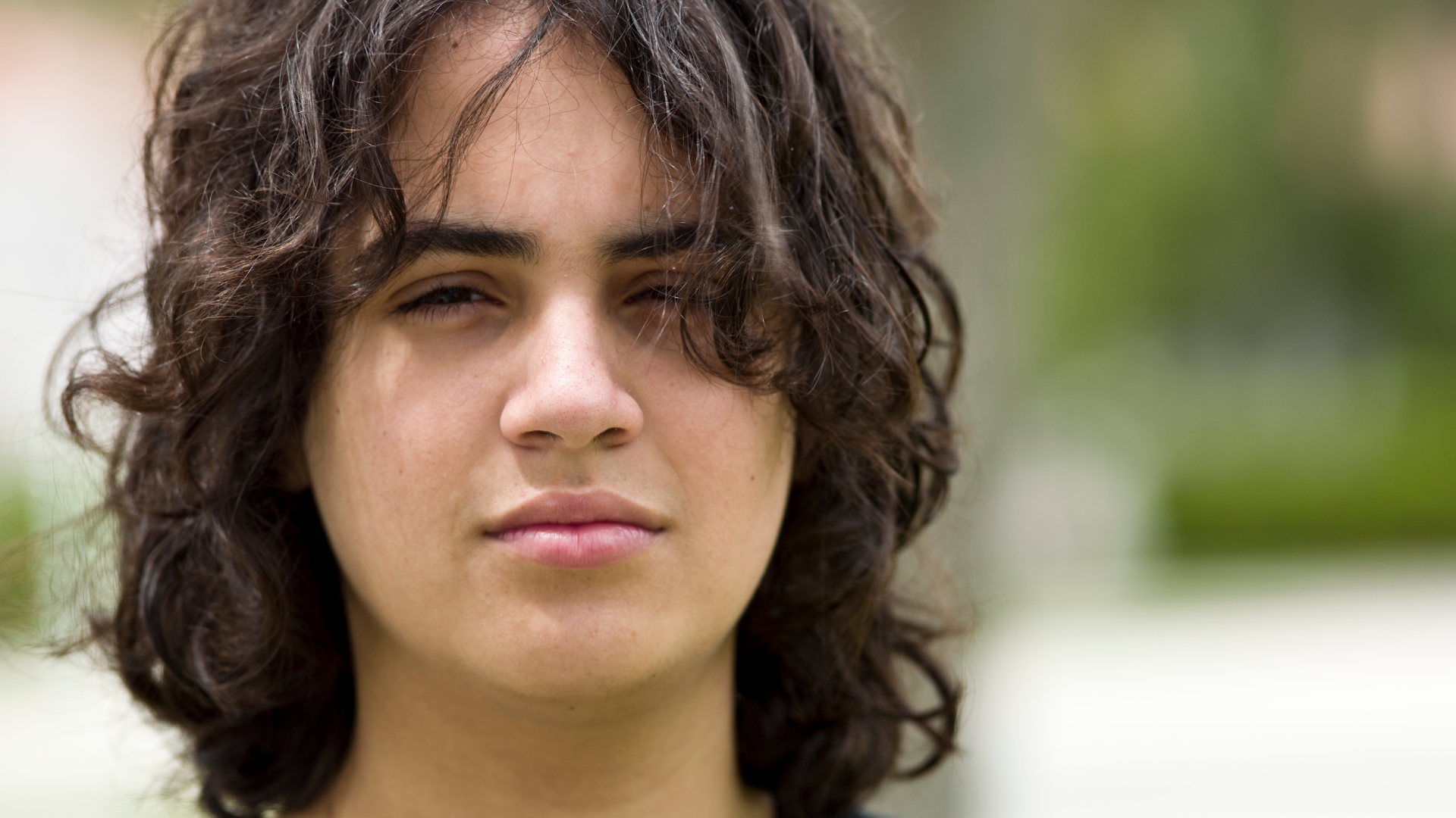 A long-haired boy stares at the camera.