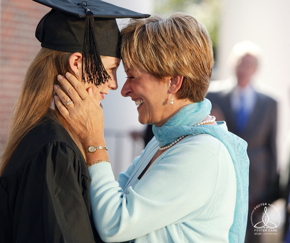 A teen girl wears a graduation cap and gown.  A middle aged woman cups her face and smiles proudly at her.