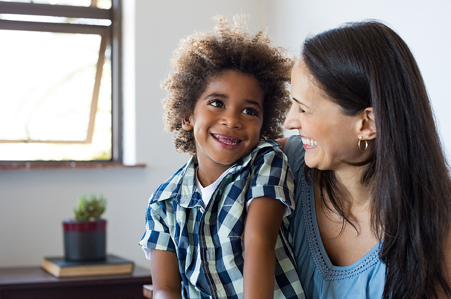 Mother with son on lap smiling with missing teeth