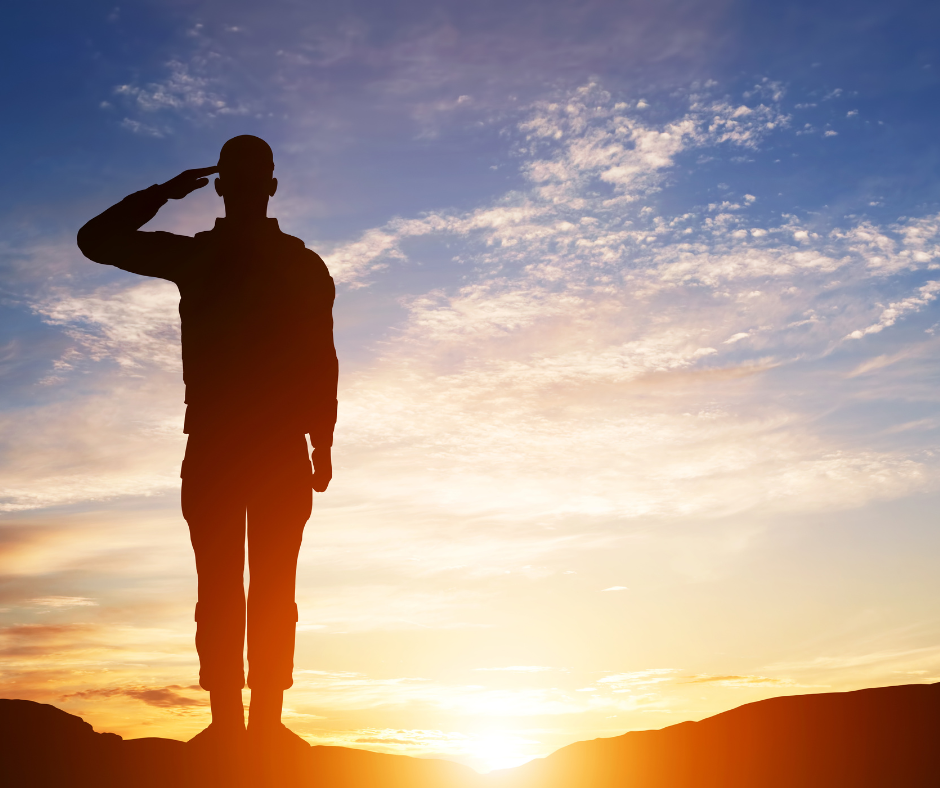 A silhouette of a soldier saluting toward the sunset.