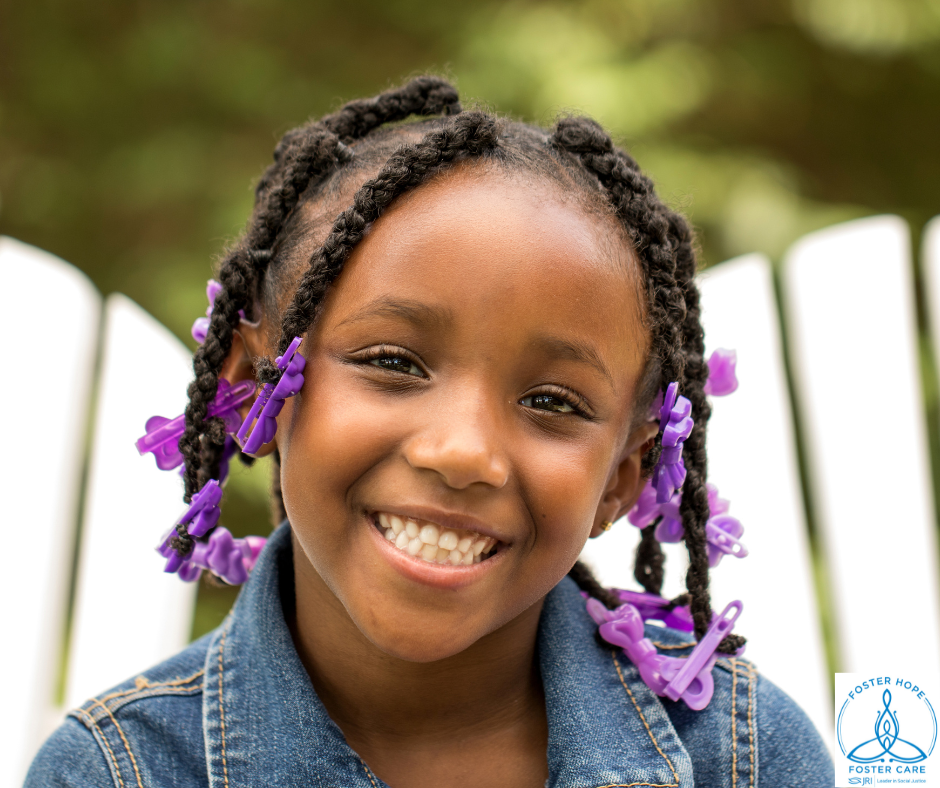 A young girl of African heritage wears her hair in braids with purple beads.