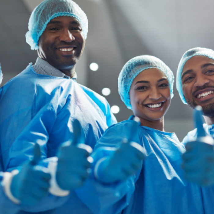 A group of diverse hospital staff in scrubs giving thumbs up