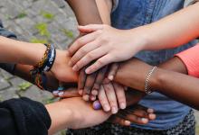 a group of hands from different individuals piled on top of each other