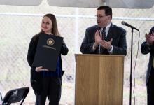 Courtney Edge-Mattos holds a the proclamation from the Governor while Michael Pay of DCF applauds at the podium.