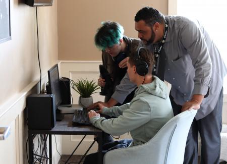 students and staff gathered around a computer at Meadowridge