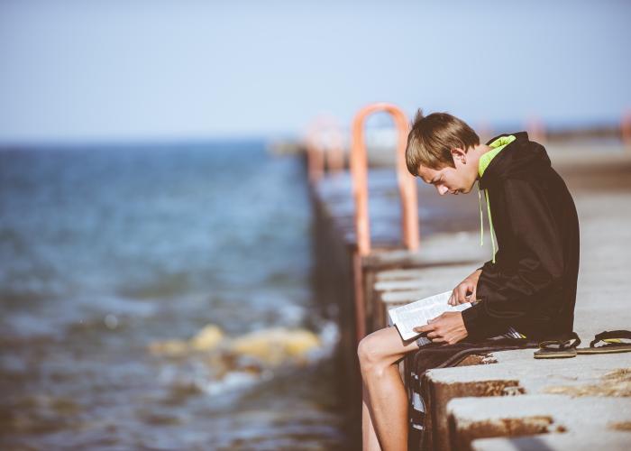 Boy reading by water