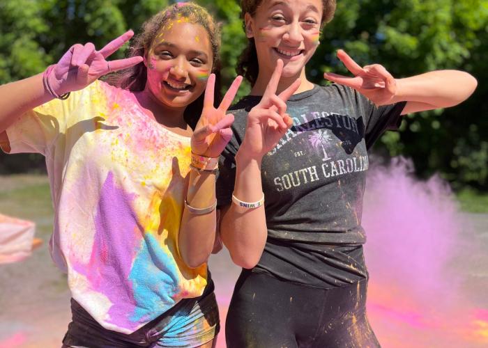 Two students smiling covered in colorful throw powder