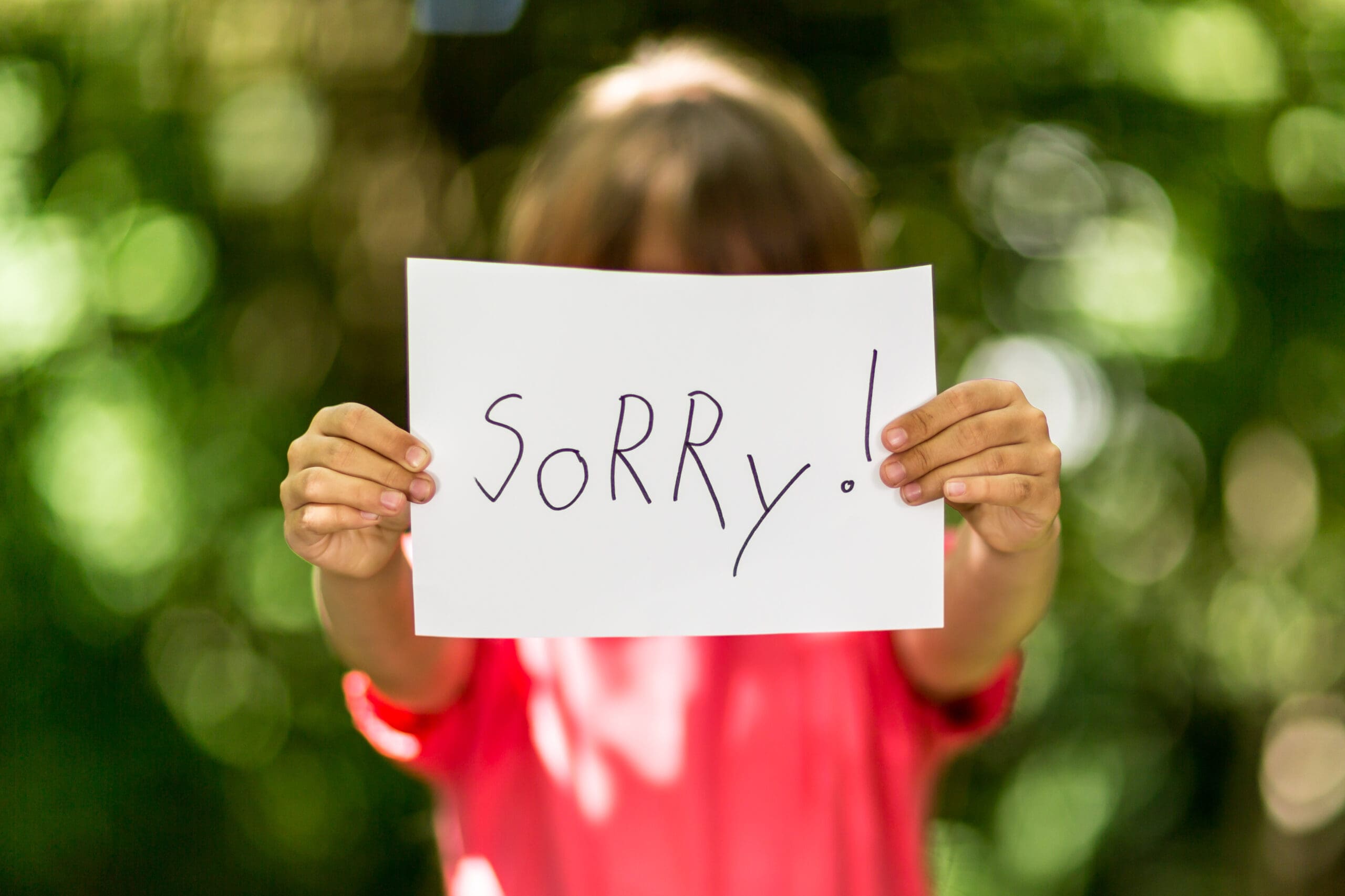 Child holding a sign that says "Sorry!"