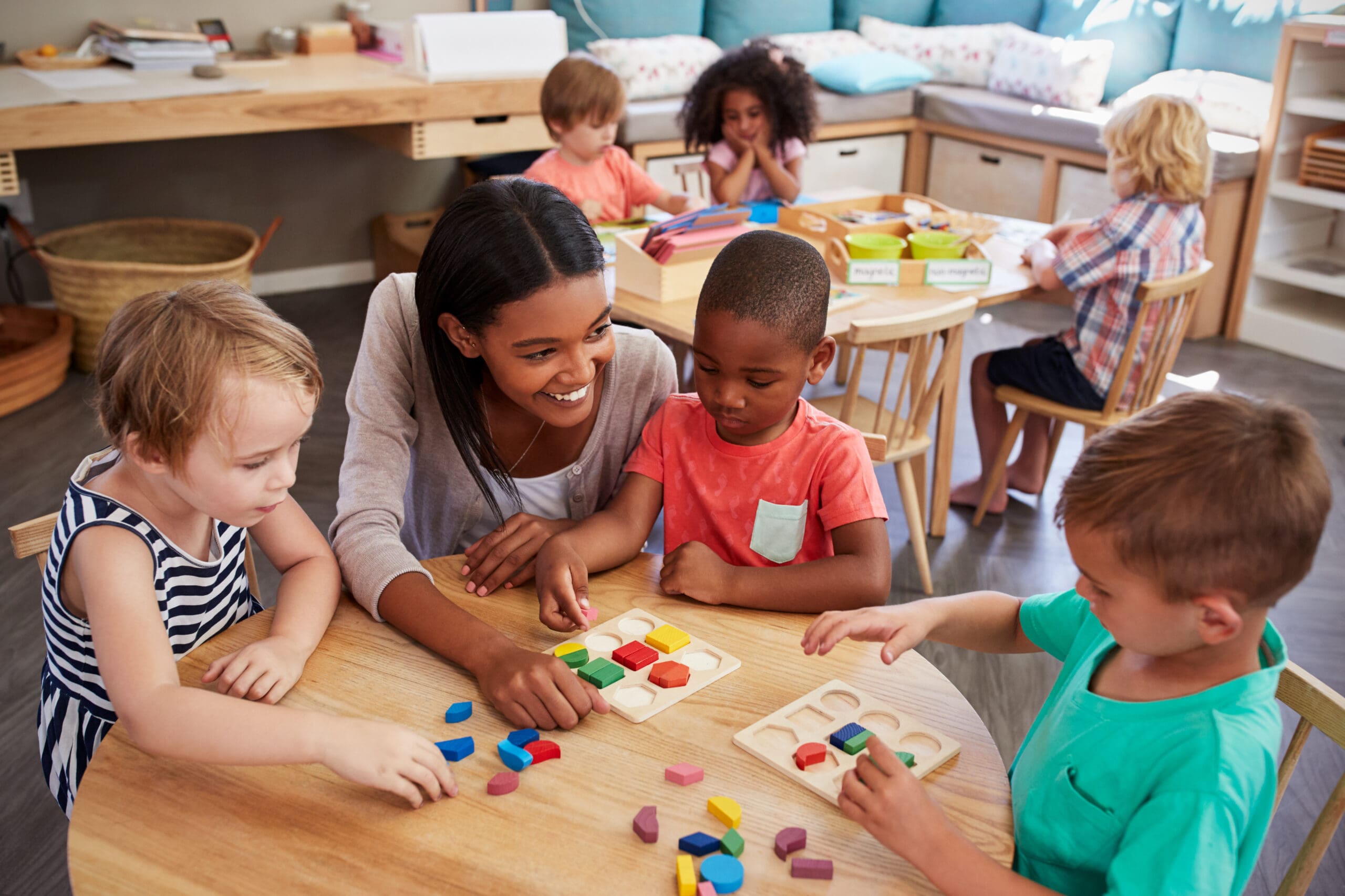 Woman playing with children with educational toys at a table in a classroom