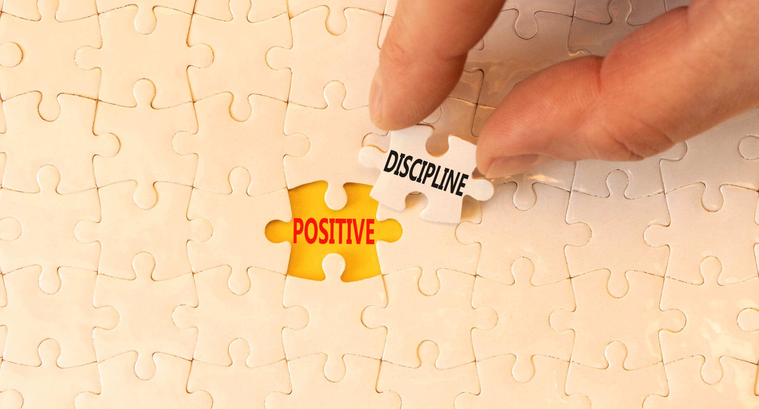 Hand placing a puzzle piece labeled 'DISCIPLINE' next to a piece labeled 'POSITIVE' on a puzzle.
