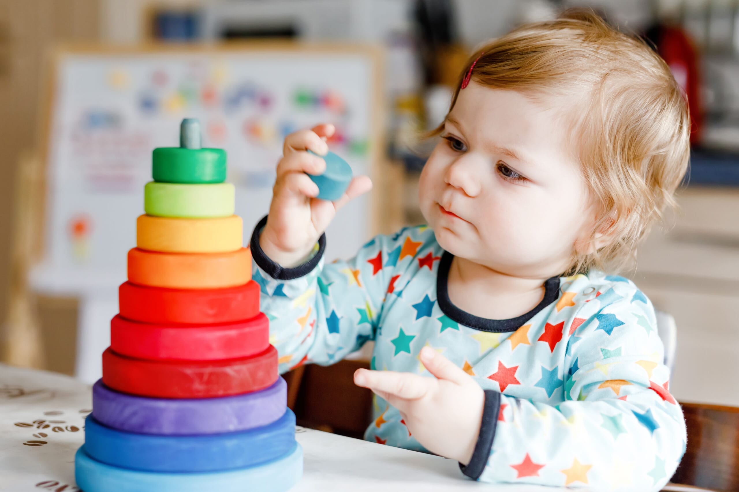 Young child stacking colorful rings on a table.