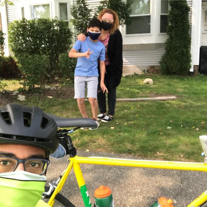 Two children and an adult outdoors, with a bicycle in the foreground.