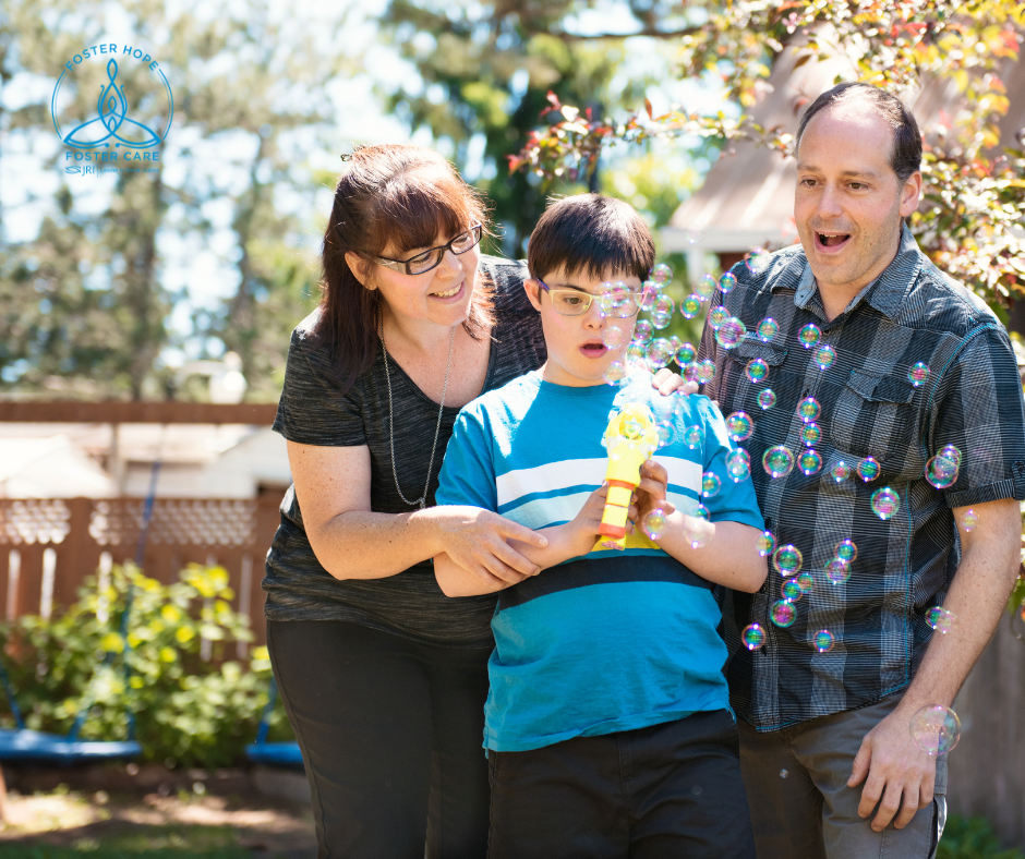 Two adults and child outdoors with bubbles, smiling and playing.