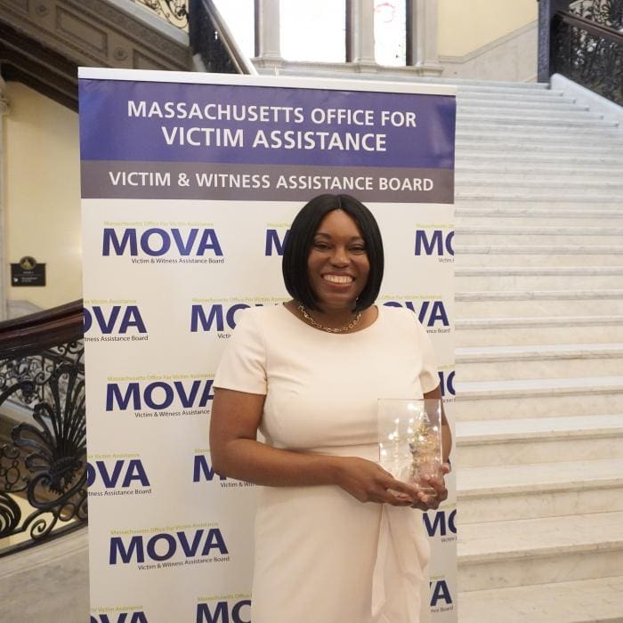 Person holding a clear award in front of a MOVA banner at a staircase.