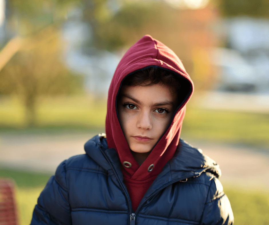 Child wearing a red hoodie and blue jacket outdoors.