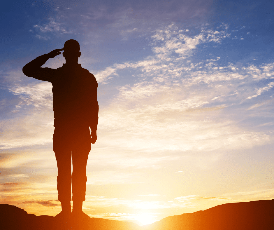 Silhouette of a person saluting against a sunset sky.