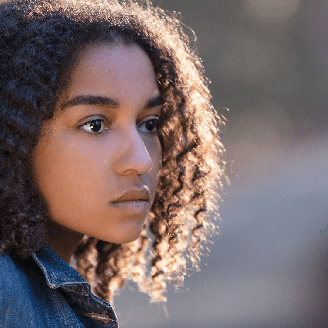 Close-up of a teenager with curly hair facing left.