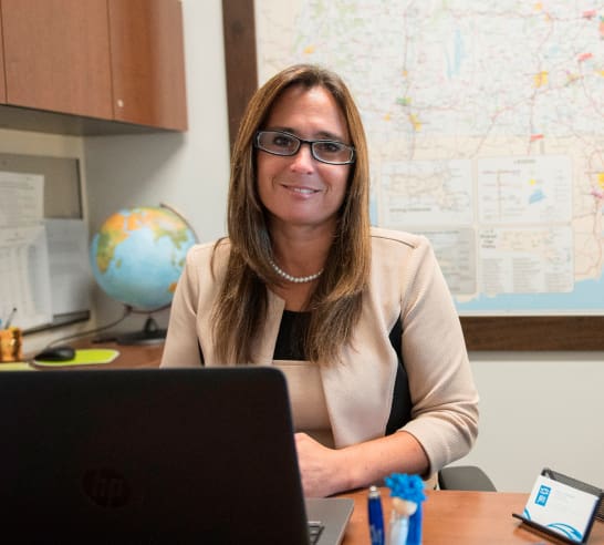 Rachel Arruda seated at desk with laptop in office setting.