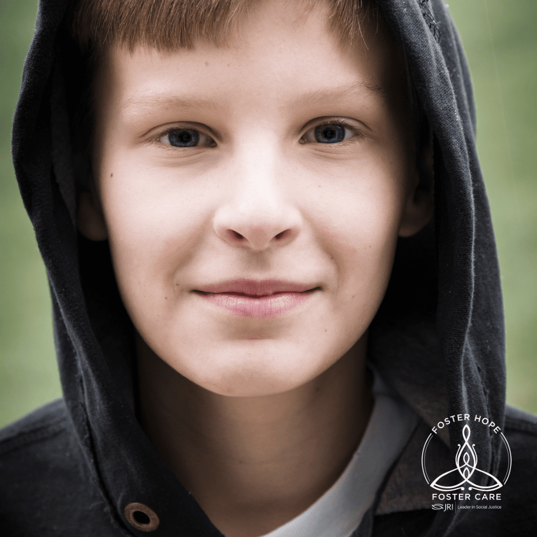 Close-up of a child's face with a black hoodie, smiling slightly.