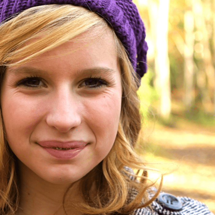 Close-up of a smiling person wearing a purple headwrap.