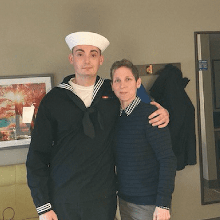 Two people standing close, one in a sailor uniform and the other in a sweater.