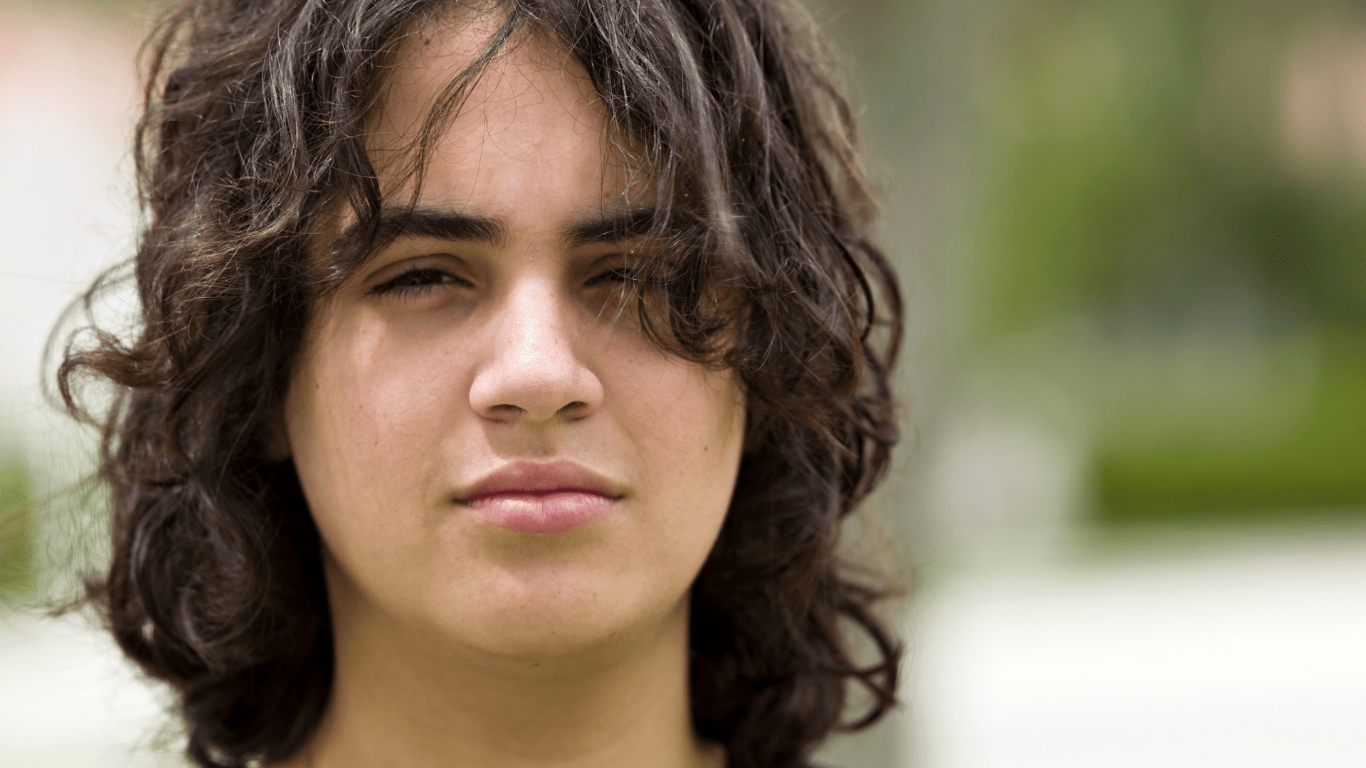 Close-up of a teenager with wavy hair looking directly at the camera.