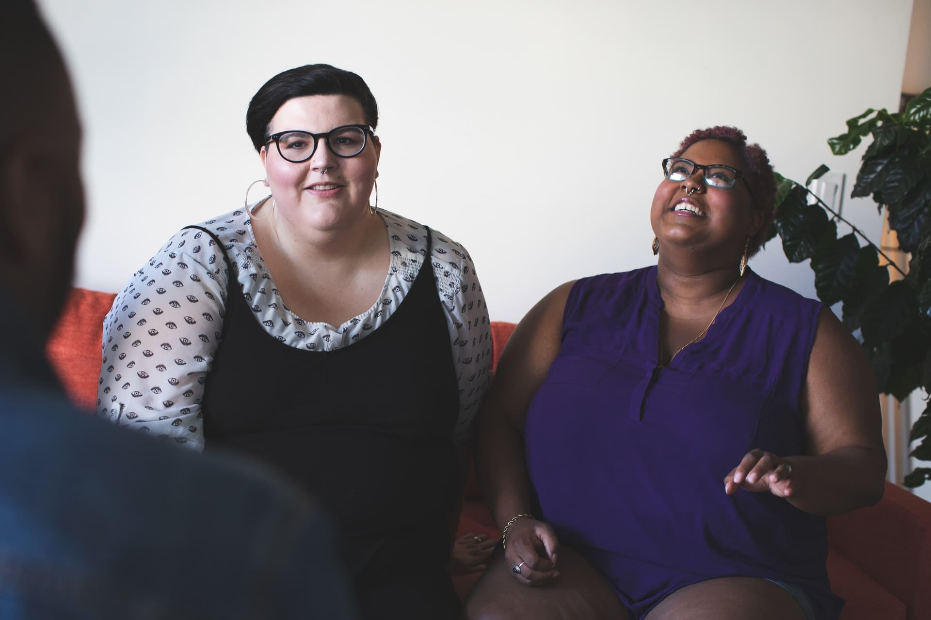 Two adults sitting on a couch, smiling during a foster parent interview.