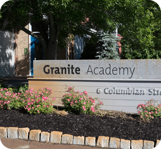 Sign reading "Granite Academy" with pink flowers in front.