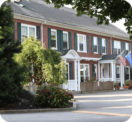 Building with white porch, flag, and trees in front