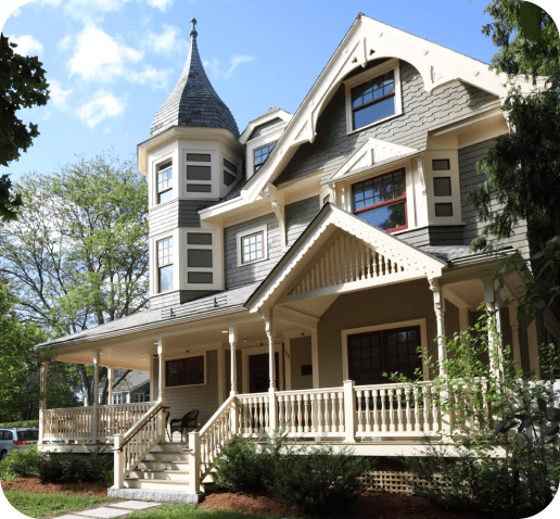 Victorian-style house with front porch and surrounding trees.