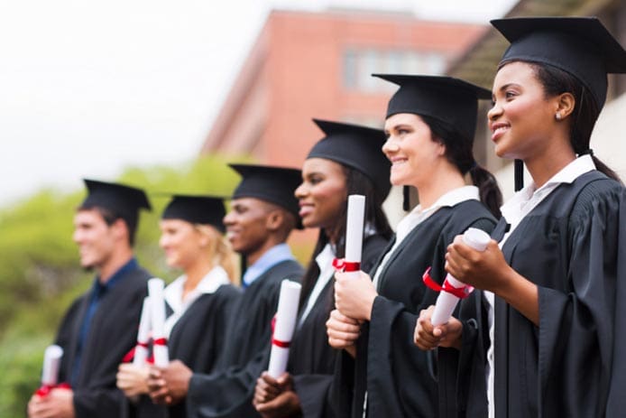 Graduates in caps and gowns holding diplomas.