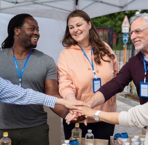 Group of volunteers holding hands in a circle, smiling.