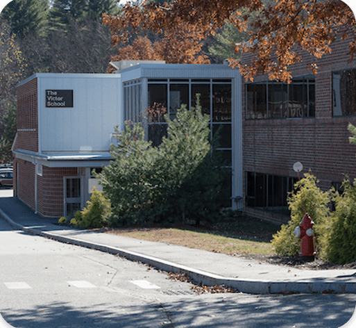 Exterior of The Victor School building with trees in the foreground.