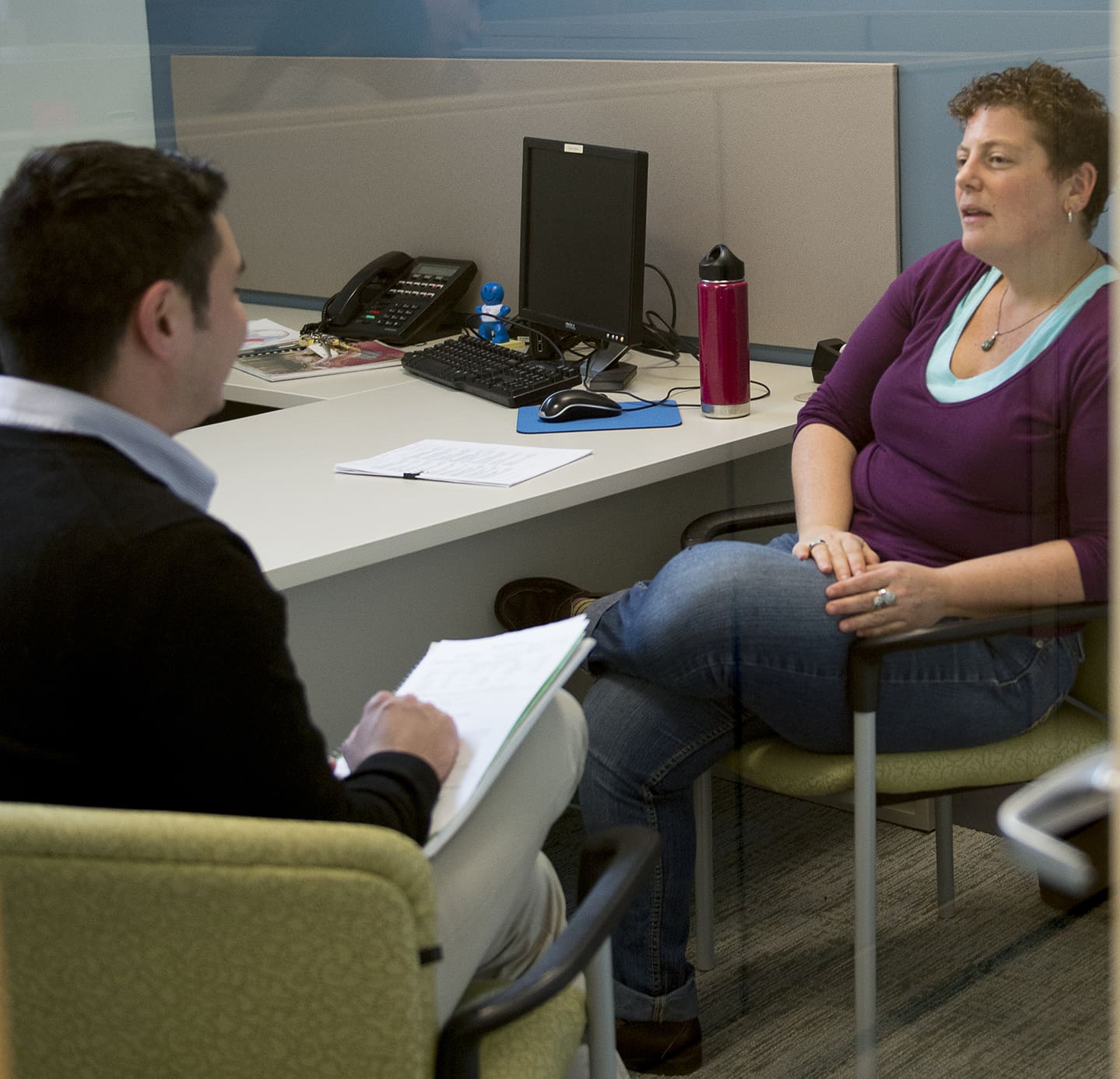 Two people in a conversation in an office, one taking notes.
