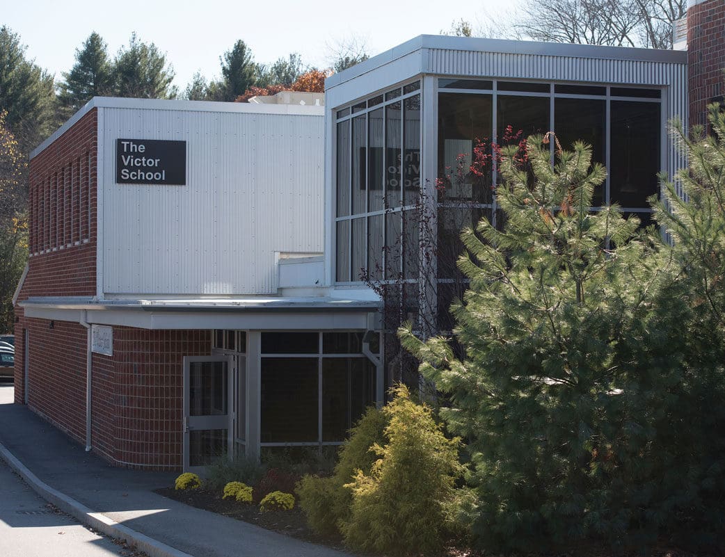 The Victor School building surrounded by trees and shrubs.