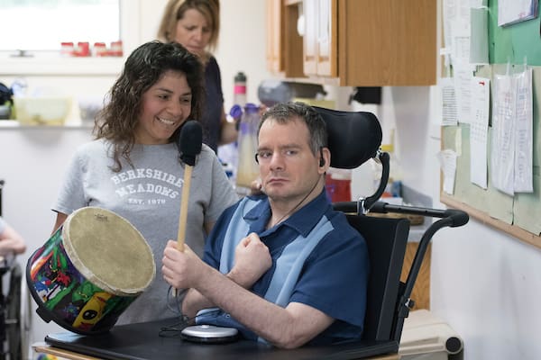 Person in a wheelchair participating in a music activity with assistance.