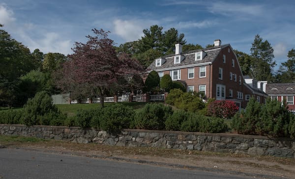 Large brick house surrounded by trees and shrubbery.
