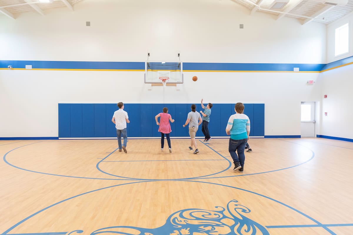 Six people playing basketball in a well-lit gymnasium.