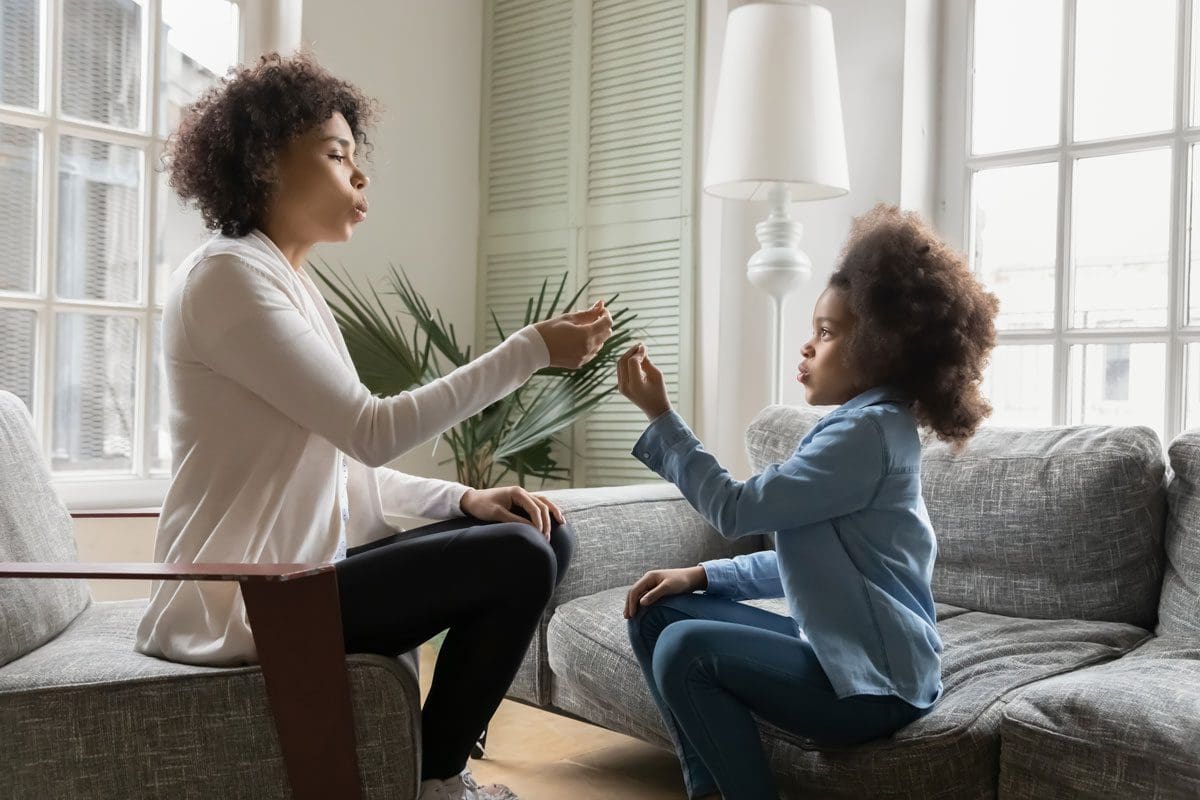Woman and girl sitting on a sofa, engaging in a conversation