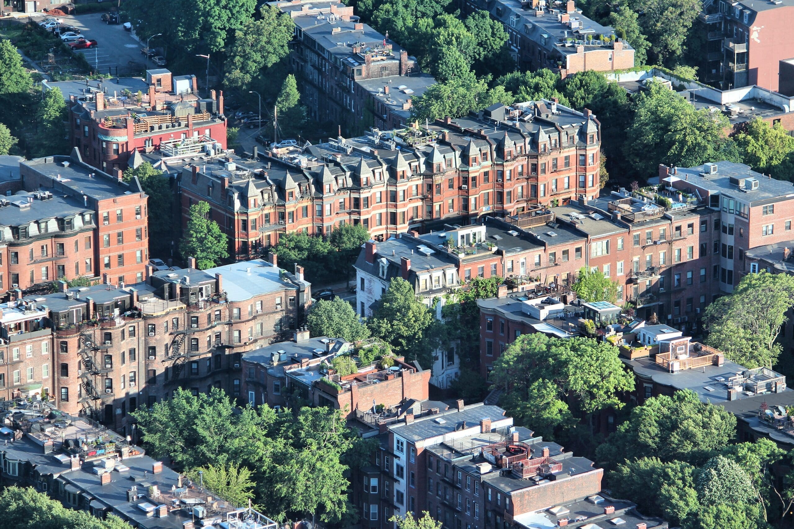 Aerial view of a Boston city block with red brick apartment buildings and green trees.