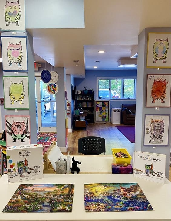 Indoor reception area with colorful artwork of monsters, bookshelves, and a window