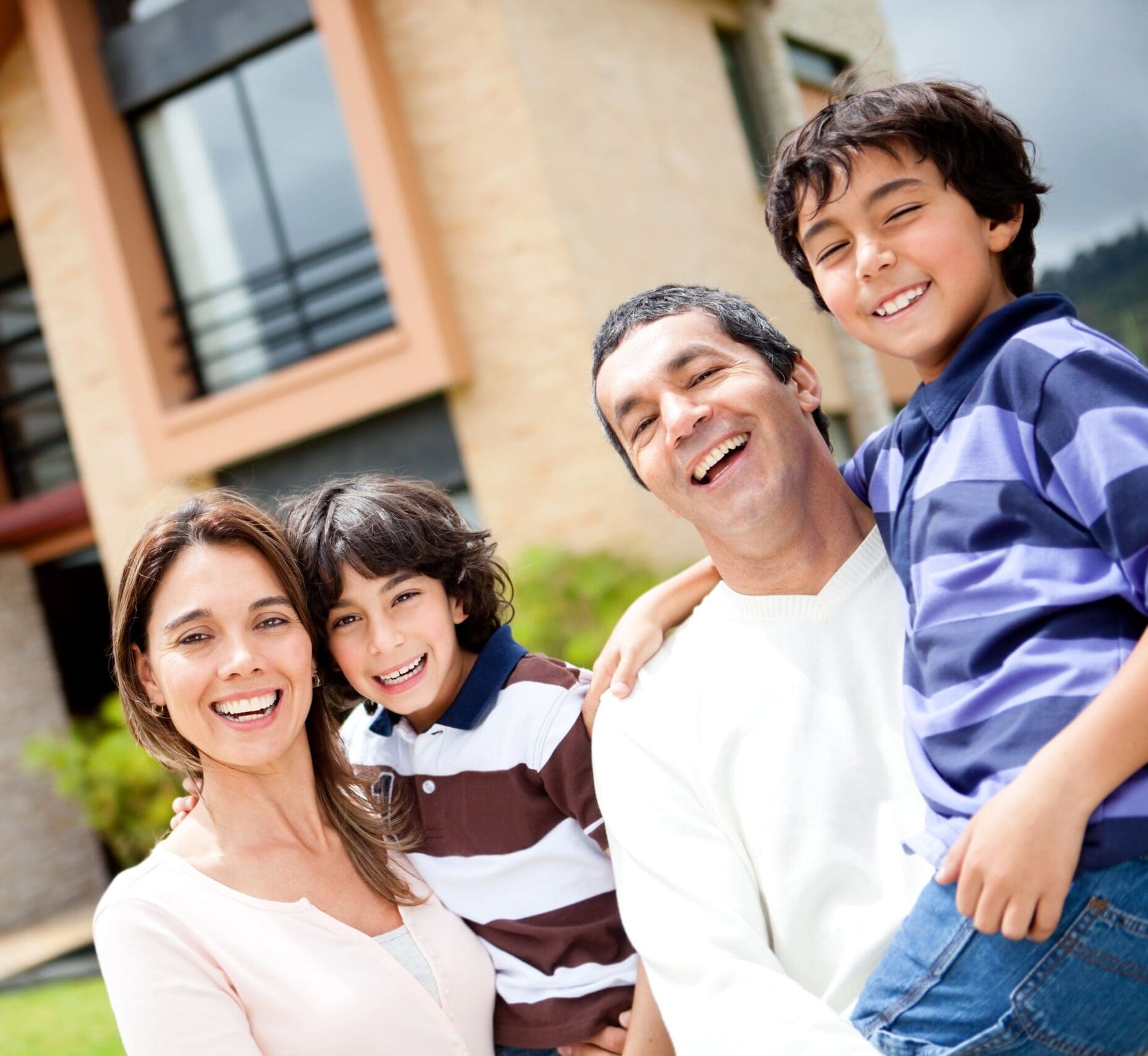 Family of four smiling outdoors in front of a building
