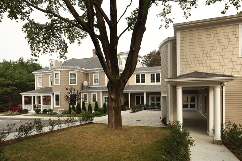 Large house with trees and a garden in front.