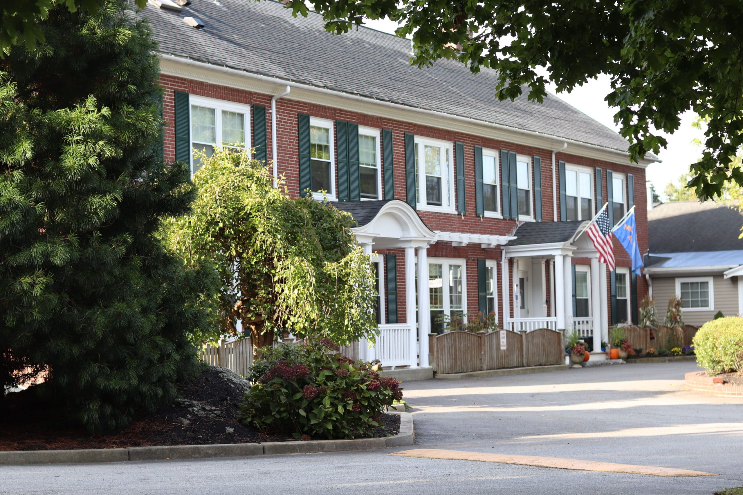 Two flags outside a red brick building with white columns.