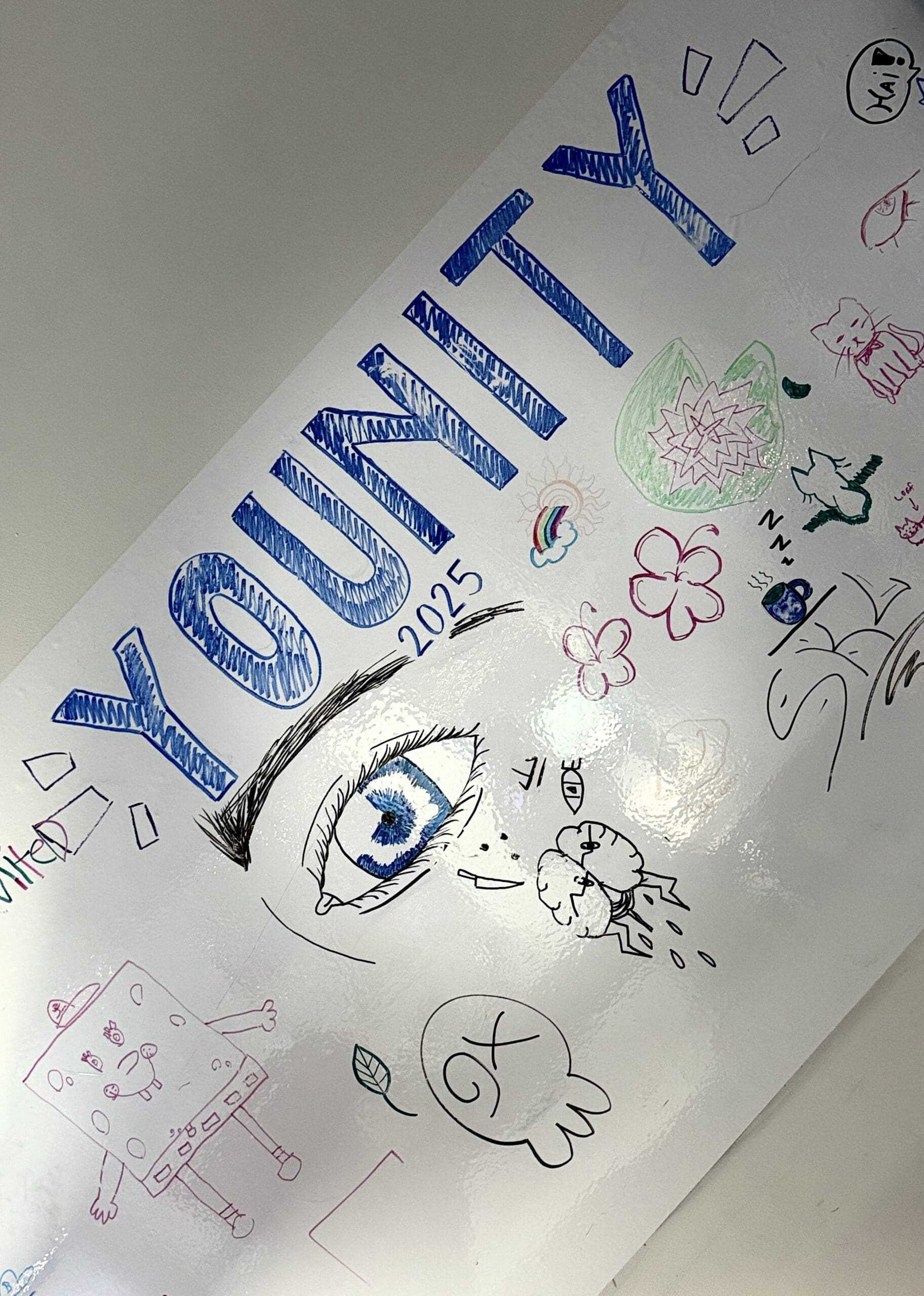 Colorful hand-drawn poster with the word 'YOUNITY' and various doodles including an eye, a rainbow, flowers, a cat, and a smiling character.