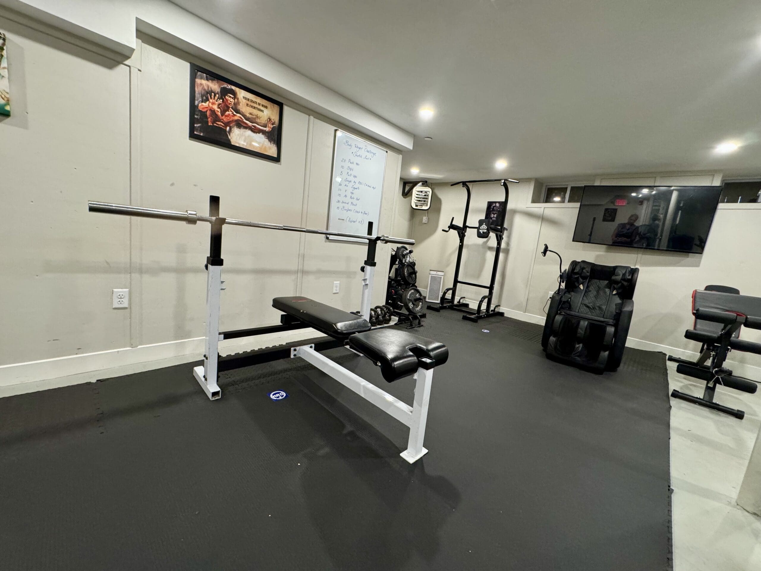 Gym with weight bench, exercise machines, and a TV on the wall